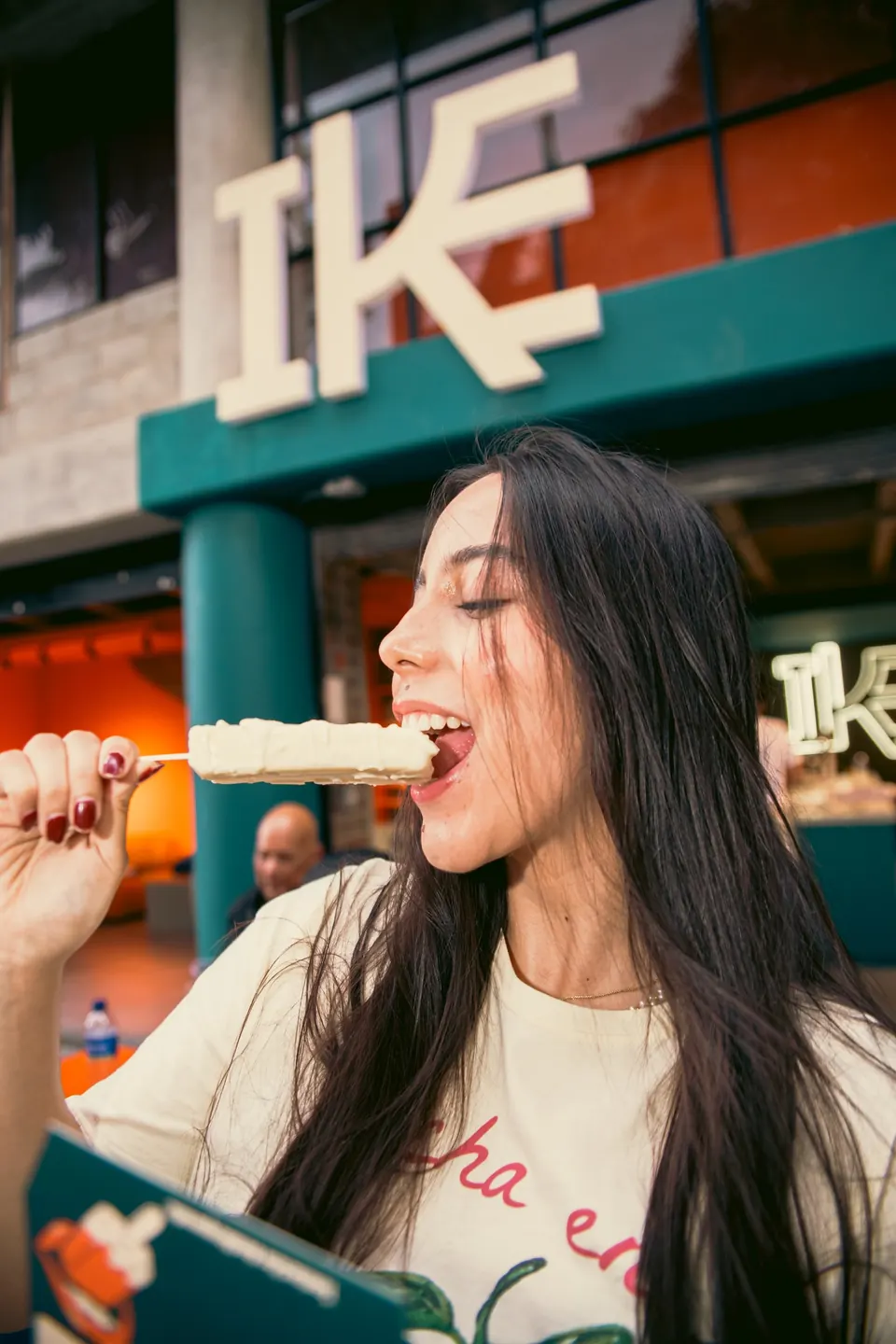 Joven comiendo una paleta cremosa IKE frente a la fachada del local en Laureles, Medellín