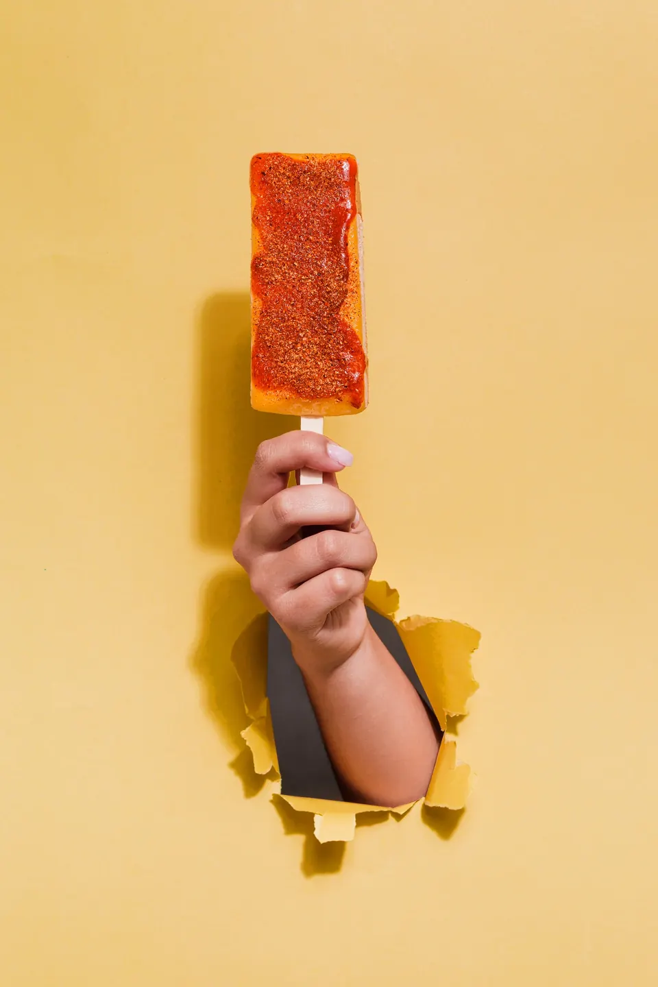 Paleta frutal IKE nivel La Atrevida con dos toppings ácidos y salsa, sobre fondo amarillo