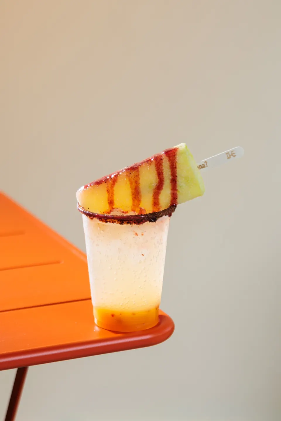 Soda IKE con paleta frutal encima sobre una mesa naranja